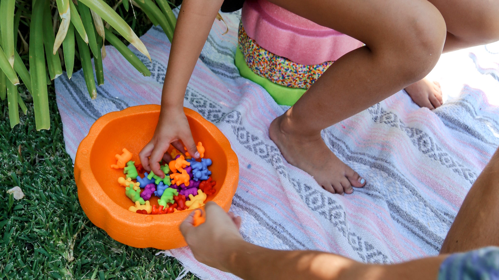 child sitting on foam stepping stones and 2 children sorting toys in an orange foam stacking stone