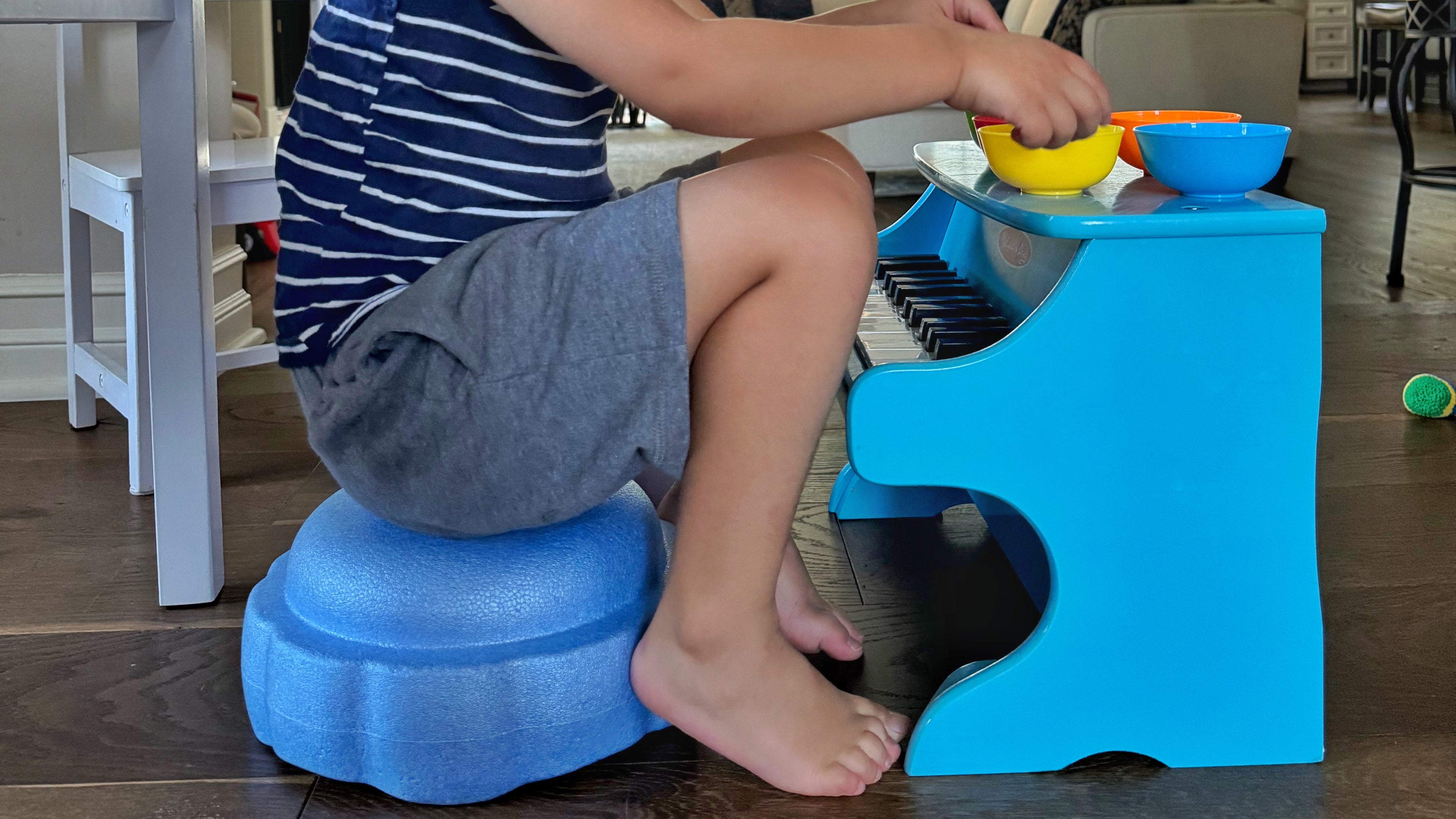 kid sitting on light blue foam stacking stone and playing with cups